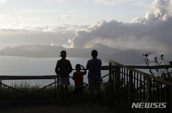 필리핀 수도 마닐라 남쪽 카비테주 따가이따이에서 14일 사람들이 호수 건너편 따알 화산이 폭발하며 내뿜는 화산재를 지켜보고 있다. AP/뉴시스