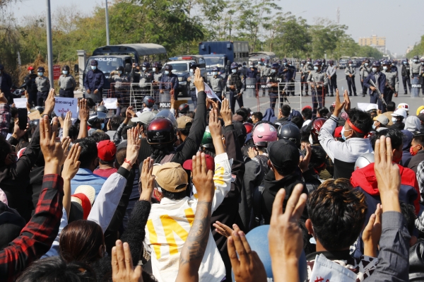 9일 미얀마 만달레이에서 군사정부 반대 시위대가 저항의 상징인 세 손가락 경례를 하며 경찰과 대치하고 있다. 미얀마 군사정부 반대 시위대가 양곤과 만달레이 등지에 내린 계엄령으로 시위가 금지됐음에도 다시 거리로 나와 시위를 이어가고 있다. 뉴시스