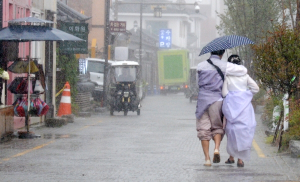 전북 전주시에 게릴라 호우가 내리기 시작한 12일 오후, 전주한옥마을 향교 인근에서 관광객들이 우산으로 비를 피하며 발걸음을 옮기고 있다. 뉴시스