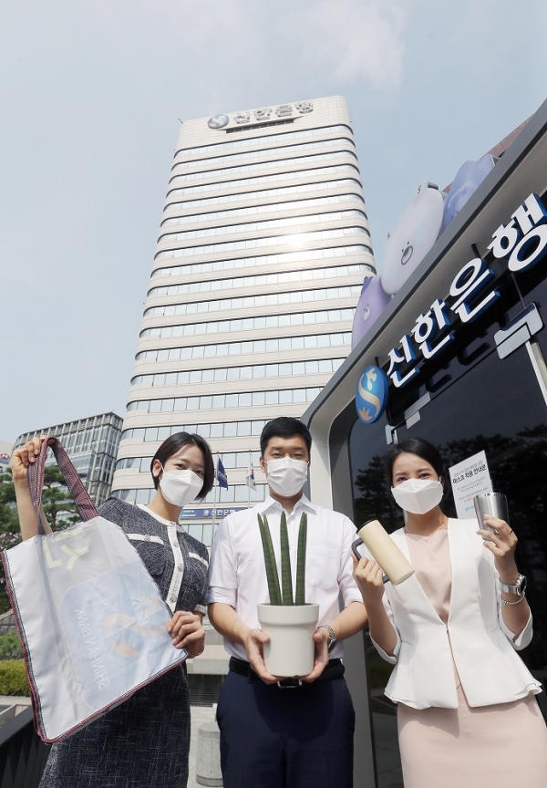신한은행 직원들이 12일 서울 중구 본점 앞에서 폐현수막을 새활용한 장바구니와 공기정화식물 스투키, 텀블러를 들고&nbsp;‘신한&nbsp;ESG&nbsp;실천 빌딩’&nbsp;선언에 동참하고 있다.&lt;신한은행&gt;