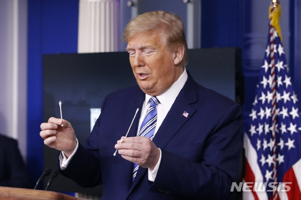 도널드 트럼프 미국 대통령이 코로나19 일일 브리핑에서 코로나19 검사용 면봉과 일반 면봉을 비교해 보이고 있다. 뉴시스