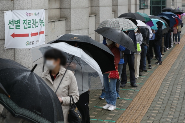 국내 코로나19 신규 확진자 수가 587명으로 집계된 12일 서울 중랑구 보건소에 마련된 코로나19 선별진료소에서 시민들이 우산을 쓰고 대기하고 있다. 뉴시스