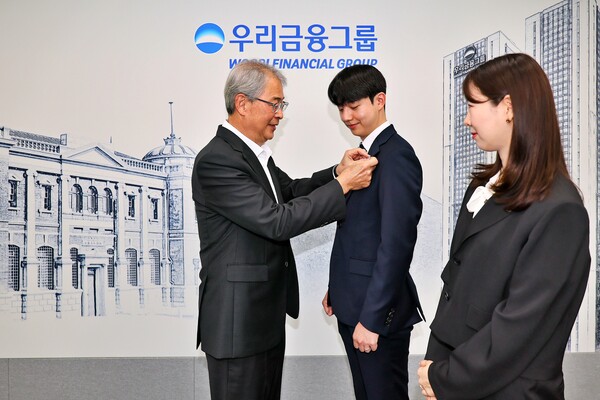 임종룡 우리금융그룹 회장이 7월 1일 서울 중구 본사에서 그룹의 새 가족이 된 동양생명·ABL생명 직원에게 디지털 선도의 의미가 담긴 새로운 그룹 보조휘장을 달아주고 있다.<우리금융지주>